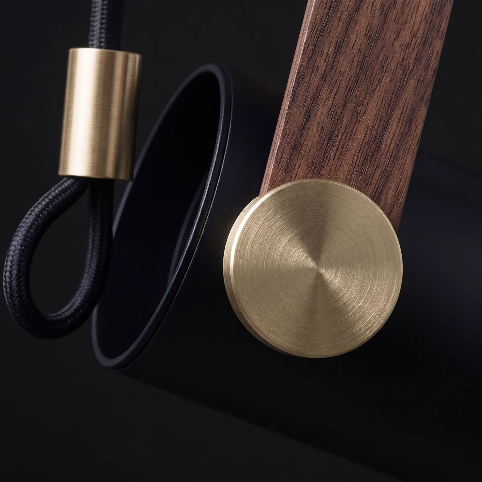 The brushed-brass pivot disc, walnut-grain strap and braided cable, close up
